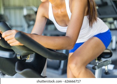 Woman Doing HIIT Cardio Workout In Indoors Gym Bike. Woman Cyclist Working Out Biking Interval Training On Indoor Bicycle.