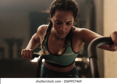 Woman Doing Intense Workout On Gym Bike. Fitness Female Using Air Bike For Cardio Workout At Gym.