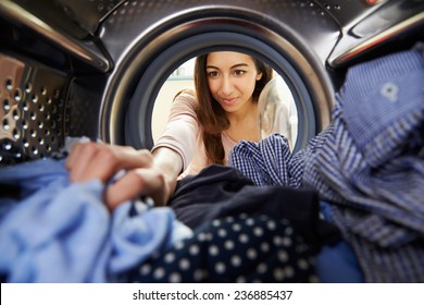 Woman Doing Laundry Reaching Inside Washing Machine