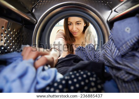 Woman Doing Laundry Reaching Inside Washing Machine