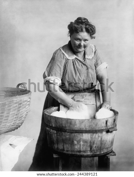 Woman doing laundry in wooden tub and metal\
washboard, ca. 1905.