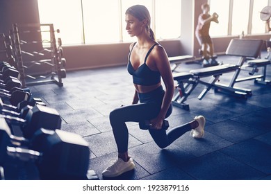 Woman doing lunges exercise with dumbbells in gym. - Shutterstock ID 1923879116