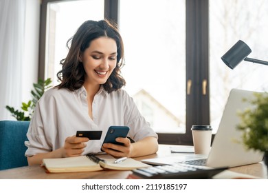 Woman is doing online purchases. Girl is doing shopping using phone and credit card at home. - Powered by Shutterstock