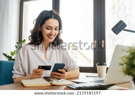 Woman is doing online purchases. Girl is doing shopping using phone and credit card at home.