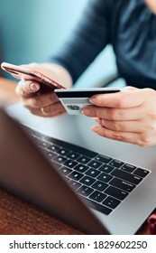 Woman doing online shopping using debit card and laptop. Female hands holding credit card over a keyboard of laptop sitting at a desk buying goods online from home