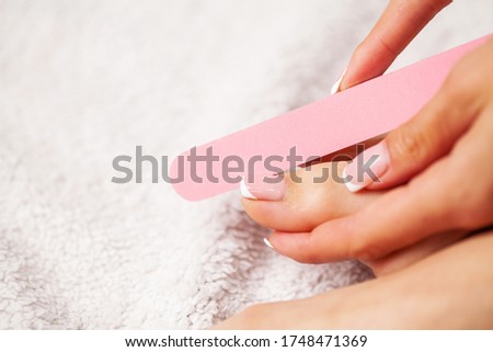 Woman doing a pedicure on her feet in the apartment