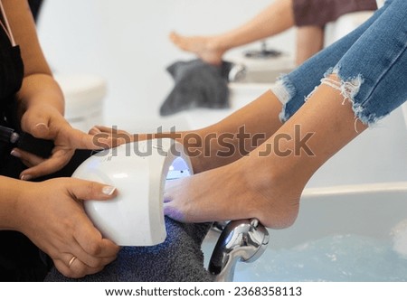 Woman doing pedicure with a professional nail dryer