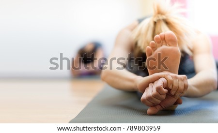 Woman doing physical exercise and stretching legs on a mat, foot close up, healthy lifestyle concept