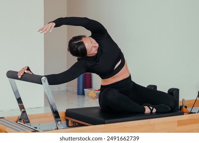 Woman doing Pilates exercise on pilates reformer bed - Powered by Shutterstock