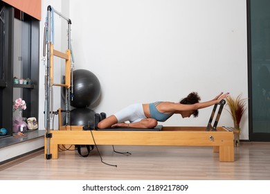 Woman doing pilates moves with reformer in studio - Powered by Shutterstock