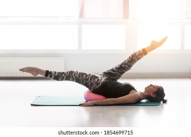 woman doing pilates with a small ball on the floor