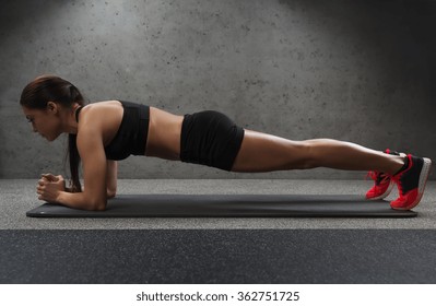 Woman Doing Plank Exercise On Mat In Gym