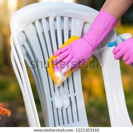 woman doing plastic chair cleaning with spray foam, close-up 