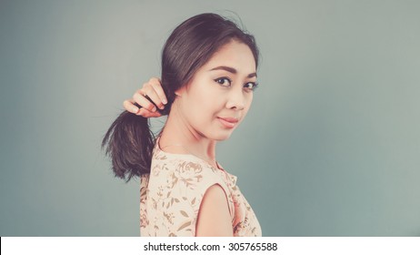 Woman Is Doing Pony Tail. Vintage, Retro Style Of Portrait Of Asian Woman In Pink Vintage Dress On Blue - Green Background.