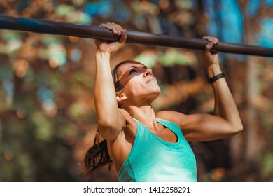 Woman doing pull-ups in the park   - Powered by Shutterstock