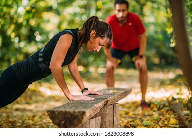 Woman doing push-ups in the park with personal trainer - Powered by Shutterstock