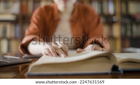 Woman doing research in a library, reading information in a large encyclopedia