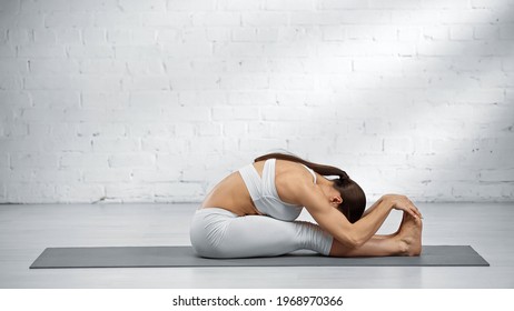 Woman Doing Seated Forward Fold Yoga Pose At Home