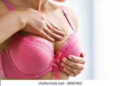 Woman doing self breast examination using pink bra
