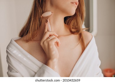 Woman doing self massage with rose quartz face roller