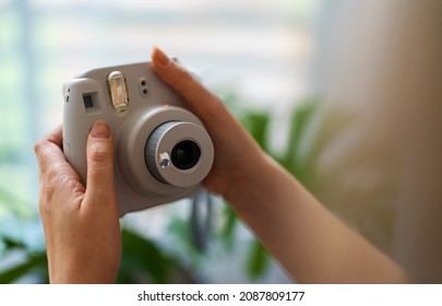 Woman doing selfie photo with instant camera.