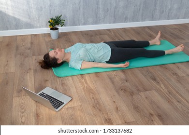 Woman Doing Shavasana Yoga Pose At Home During Online Yoga Class