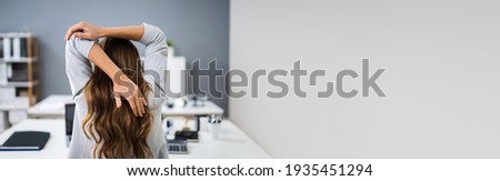 Woman Doing Stretching Exercise In Office At Desk