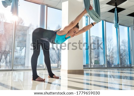 woman doing  stretching exercises using fly yoga in fitness training. Health, fly yoga concept.