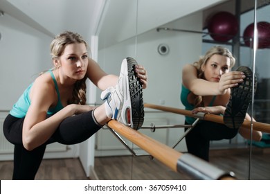 Woman doing stretching near barre in fitness center