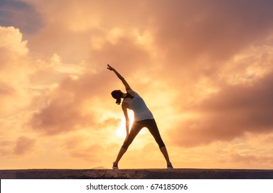 Woman doing stretching warm up exercise outdoors against a beautiful sunset.  - Powered by Shutterstock