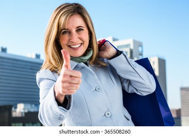 Woman doing a thumbs up during her shopping in town Foto Stock