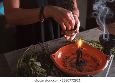 woman doing traditional ritual with black candle sea salt pepper in clay plate with herbs and incense and energy management with fire
