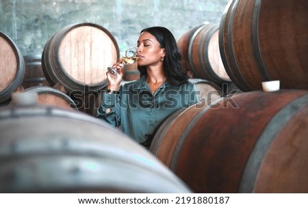 Woman doing wine tasting, drinking glass of chardonnay or sauvignon blanc in winery cellar amongst barrels on vineyard. Beautiful oenologist or sommelier enjoying a relaxing, luxury beverage indoors Foto stock © 