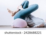 Woman doing yin yoga passive hip stretch exercises on bolster