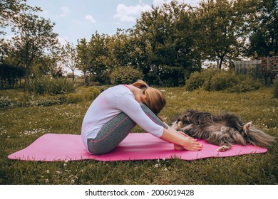 Woman Doing Yoga With Dog In Nature.