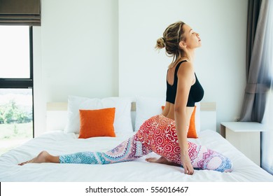 Woman Doing Yoga Exercise On Bed At Home. Morning Workout In Bedroom. Healthy And Sport Lifestyle.