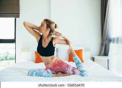 Woman Doing Yoga Exercise On Bed At Home. Morning Workout In Bedroom. Healthy And Sport Lifestyle.