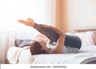 Woman Doing Yoga Exercise On Bed At Home. Morning Workout In Bedroom. Healthy And Sport Lifestyle.