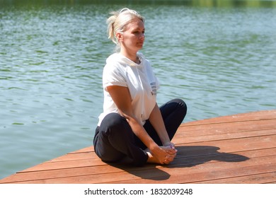 woman doing yoga exercises in city green park with lake. morning exercise outdoor