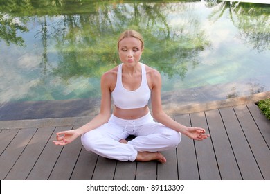 Woman Doing Yoga Exercises On Pool Deck