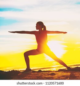 Woman Doing Yoga On Beach. Fit Girl In Warrior II Pose Standing In Silhouette Against Sun Flare Background. Square Crop For Social Media.