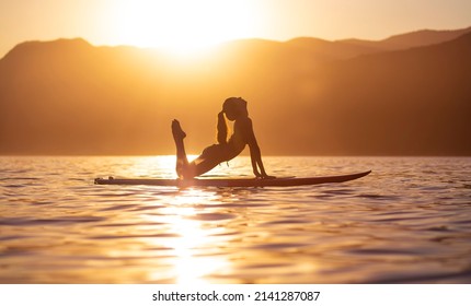woman doing yoga on sup board at sunset. outdoor summer activity. Sup yoga.