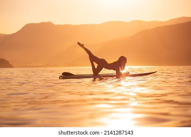 woman doing yoga on sup board at sunset. outdoor summer activity. Sup yoga.
