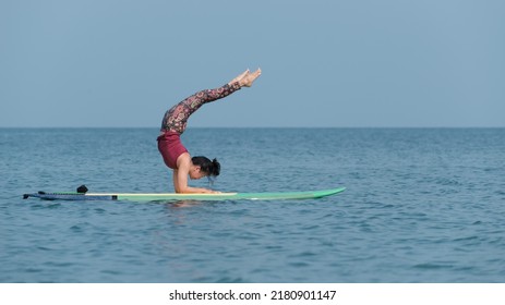 Woman doing YOGA on a SUP board in the sea. person on the beach. 