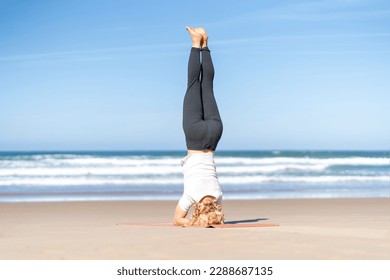 Woman doing yoga Salambha pose. Girl on supported headstand Salamba Sirsasana sirsa at the beach - Powered by Shutterstock