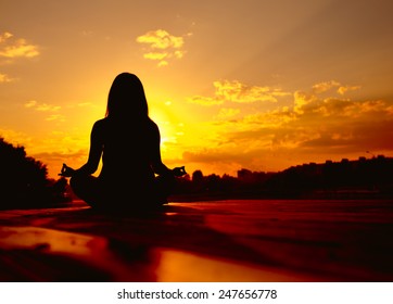 Woman doing yoga at sunset - Shutterstock ID 247656778