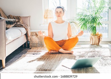 Woman Doing Yoga And Watching Tutorial Lesson On Laptop At Home.