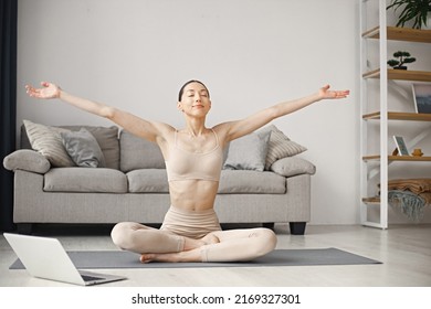 Woman Doing Yoga While Watching Online Workout Tutorials On Laptop At Home