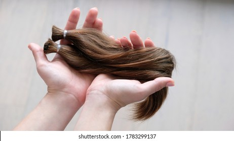 woman is donating two chopped brown hair long pony-tails to make wigs for cancer kids 