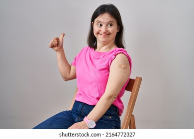 Woman With Down Syndrome Wearing Band Aid For Vaccine Injection Smiling Happy And Positive, Thumb Up Doing Excellent And Approval Sign 